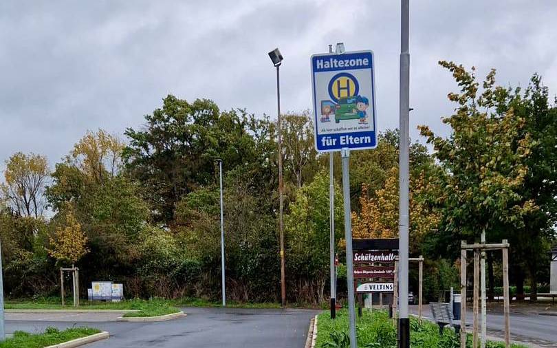 Ein blaues Verkehrsschild auf dem steht "Haltezone für Eltern".