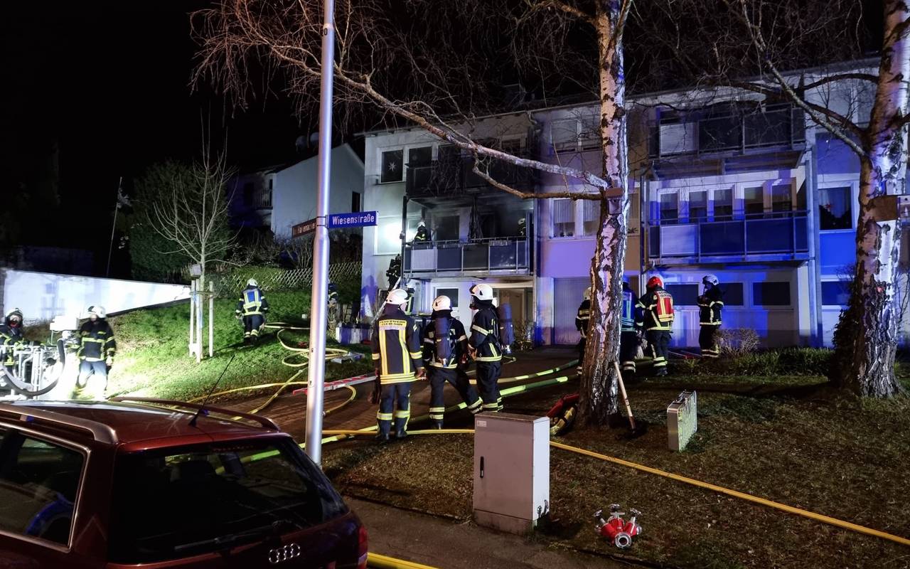 Das Bild zeigt wie Feuerwehrkräfte eine Wohnung im ersten Obergeschoss eines Mehrfamilienhauses löschen.