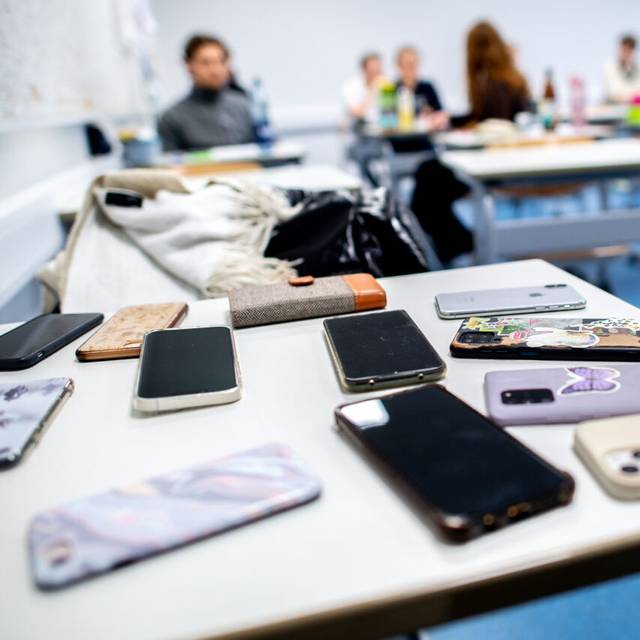 Zahlreiche Smartphones der Schülerinnen und Schüler liegen vor Beginn der schriftlichen Abiturprüfungen auf einem Tisch