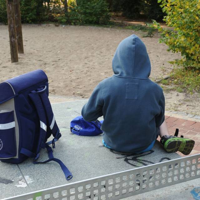 Ein Junge sitzt mit seinem Schulranzen auf einer Tischtennisplatte auf einem Spielplatz. Notorische Schwänzer oder Eltern, die ihre Kinder für einen frühzeitigen Urlaubsbeginn krank schreiben: Eine Verletzung der Schulpflicht kann unangenehme Folgen haben.