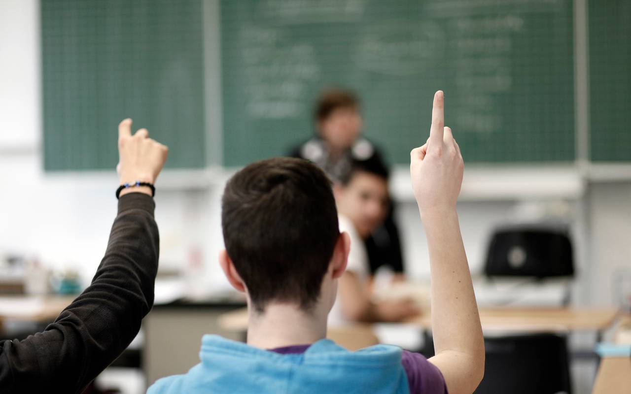 Ein Schüler hebt im Unterricht in einer Schule die Hand.
