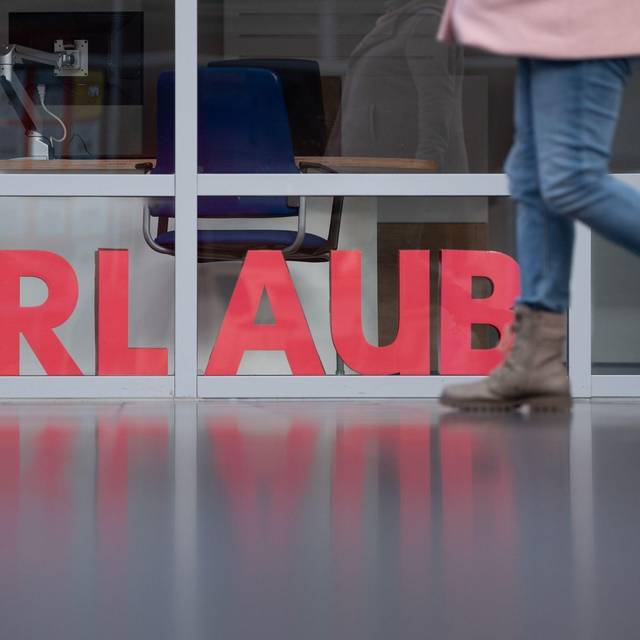 Eine Frau läuft an den Buchstaben Urlaub vorbei