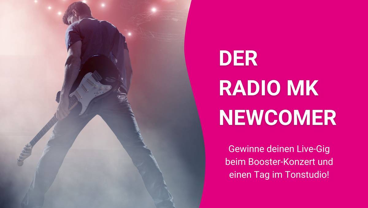 Ein Gitarrist steht mit dem Rücken zur Kamera auf einer beleuchteten Bühne. 