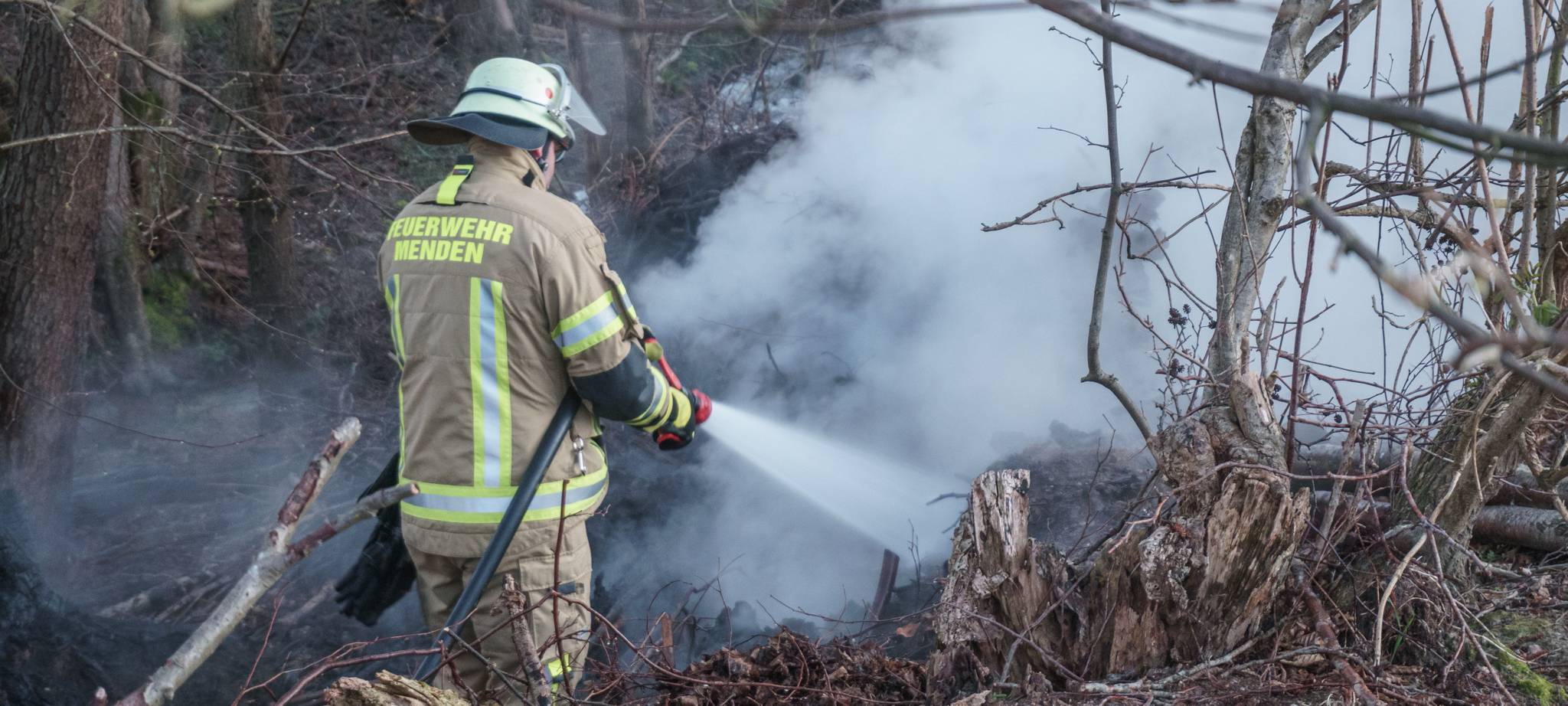 Ein Feuerwehrmann bekämpf einen Waldbrand in Menden.