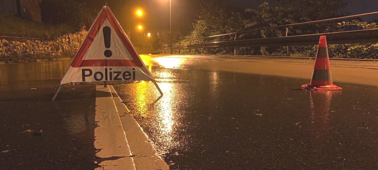 Gefahrenschild auf nasser Straße in der Nacht