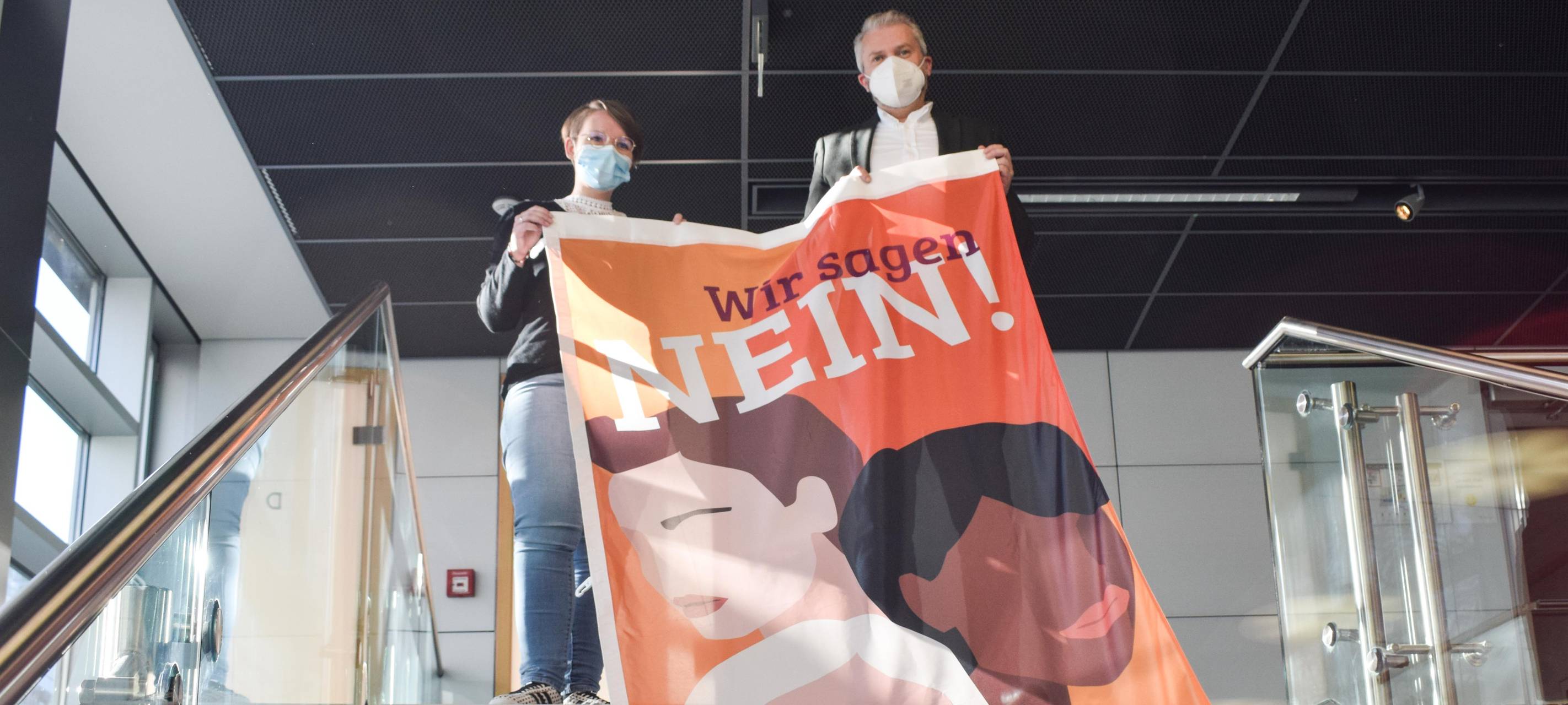 Orangene Flagge mit Frauengesicht an einem Treppenaufgang