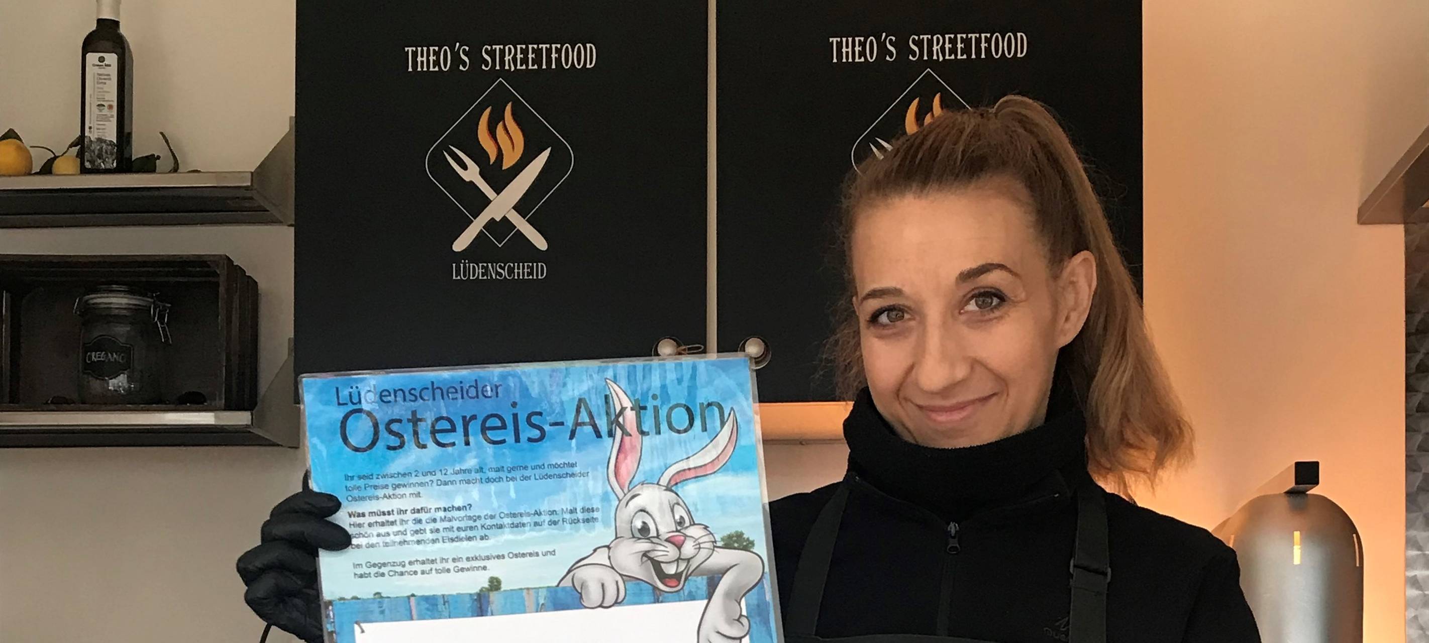 Eine Eisdielenverkäuferin hält das Ostereis-Plakat in die Luft