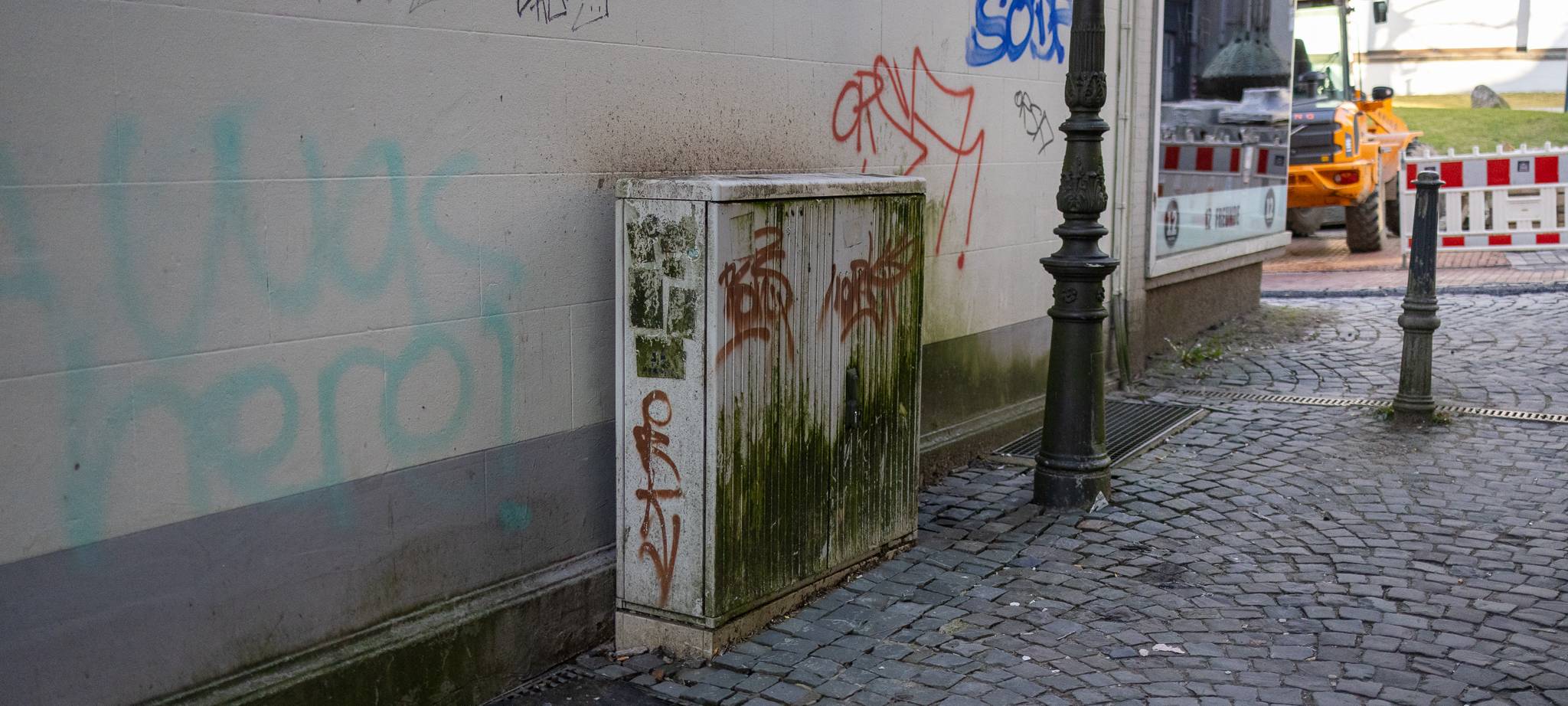 Stromkasten mit Graffiti-Besprühungen an einer Hauswand in der Lüdenscheider Innenstadt