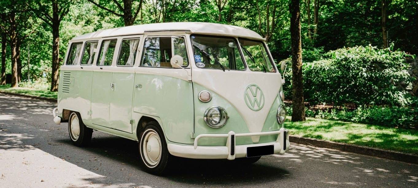 Ein hellgrüner VW T1 steht auf einem Waldweg