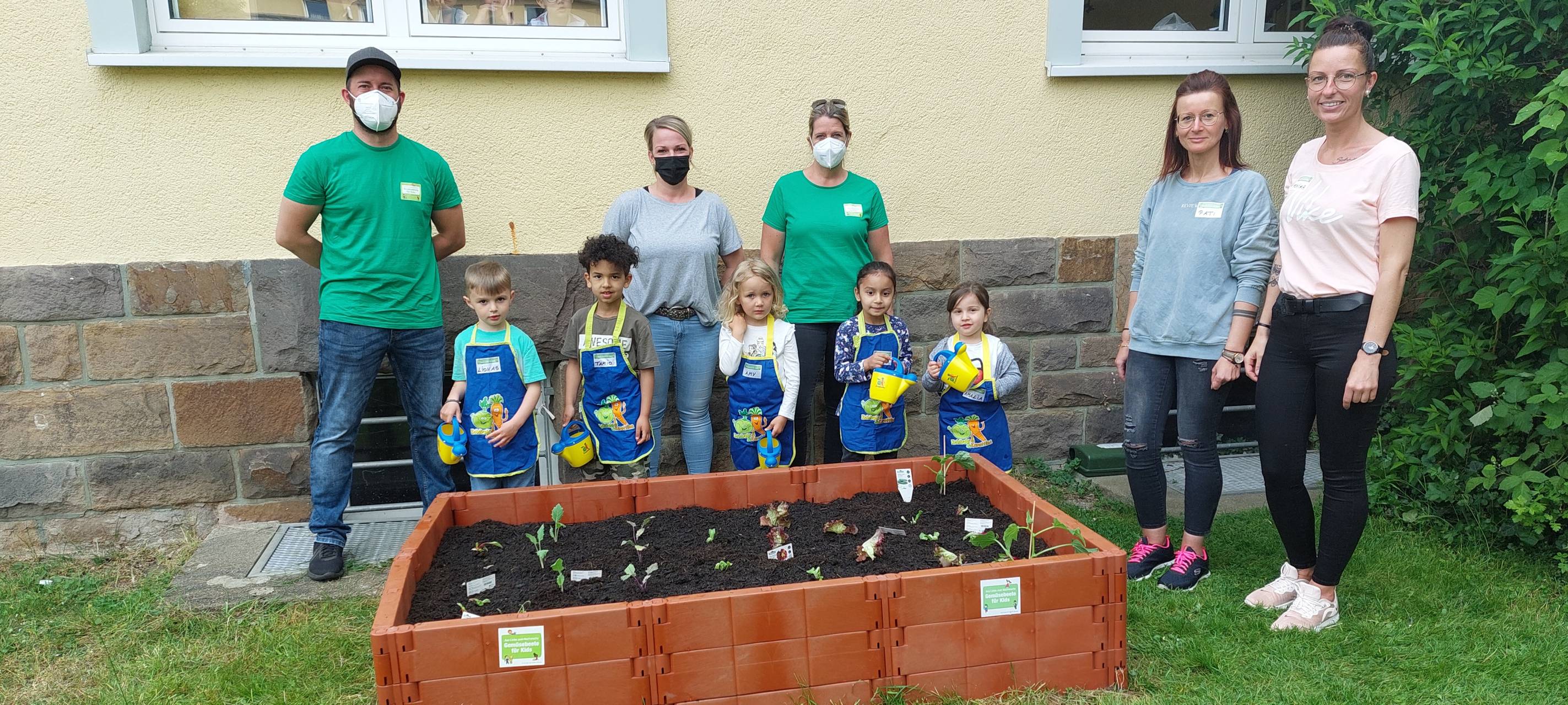 Kinder stehen vor ihrem Hochbeet