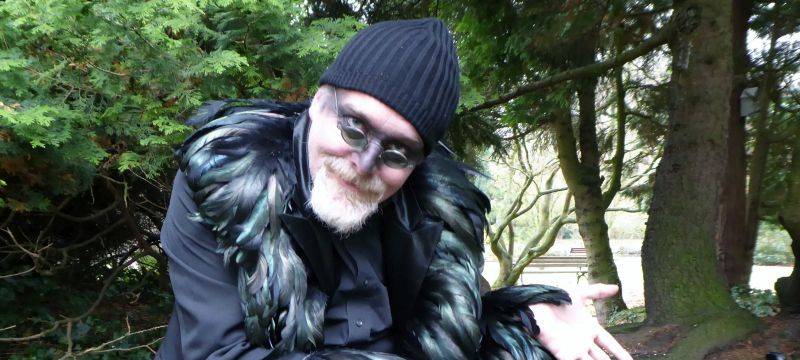 Autor Markus Veith hockt als Rabe verkleidet aur einer Bank