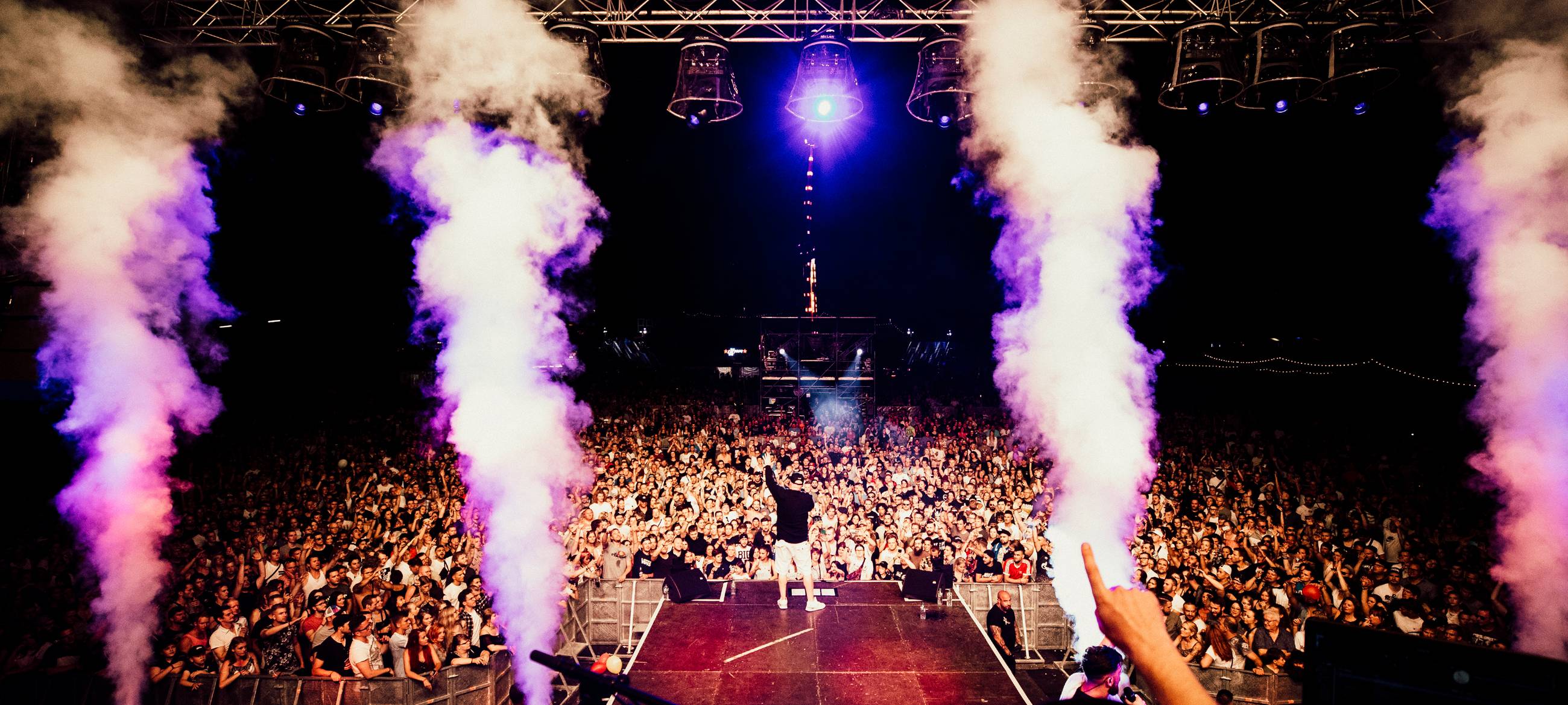 Ein Mann steht auf einer Bühne, vor ihm eine Menschenmenge