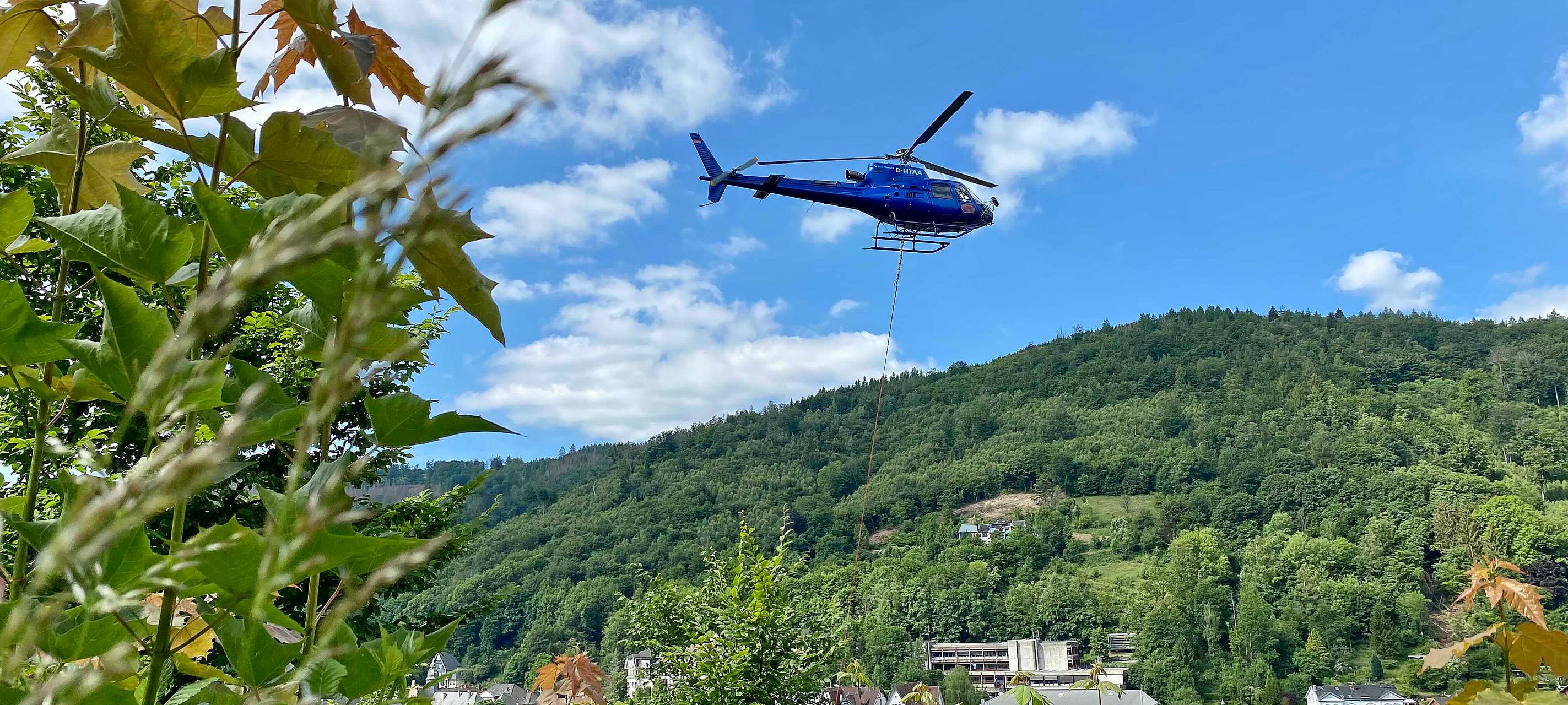 Ein blauer Hubschrauber fliegt direkt über der Burg Altena.