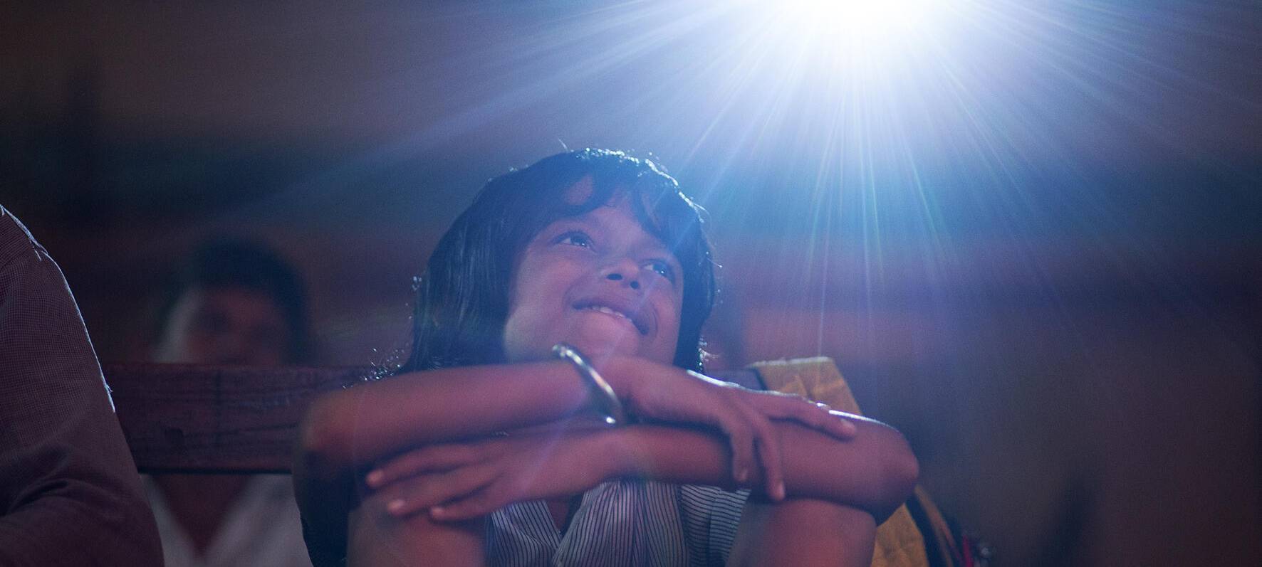 Kind schaut sich Film auf Leinwand in Kino an.