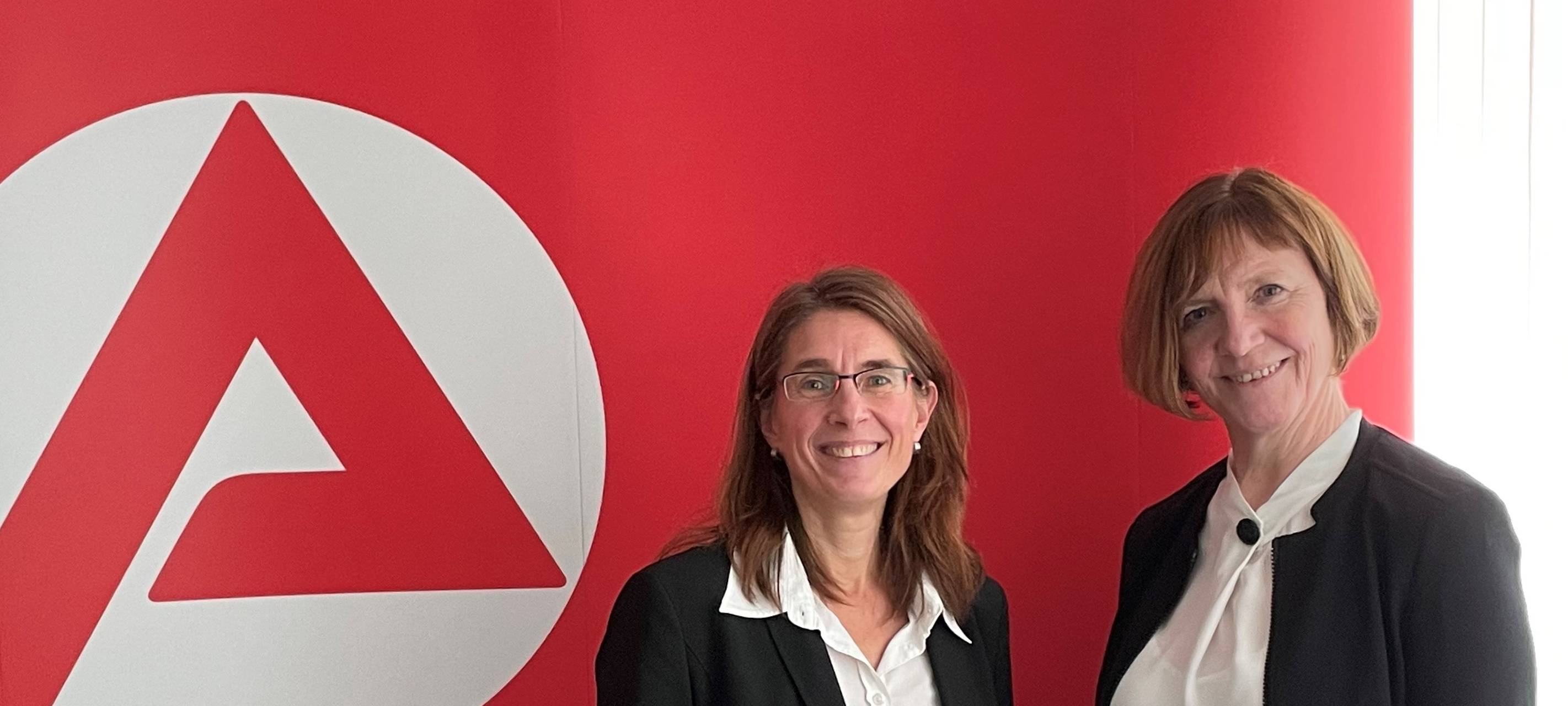 Sandra Pawlas (Agentur für Arbeit) und Renate Holke (Jobcenter) vor einem Banner der Arbeitsagentur