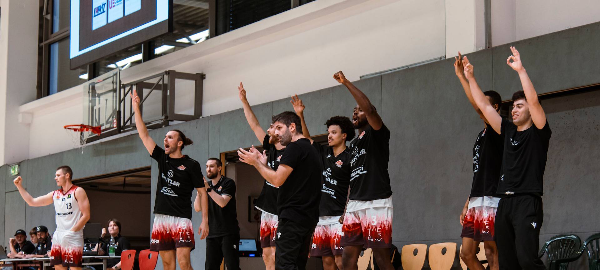 Jubelnde Basketballspieler am Rande eines Basketballfeldes.