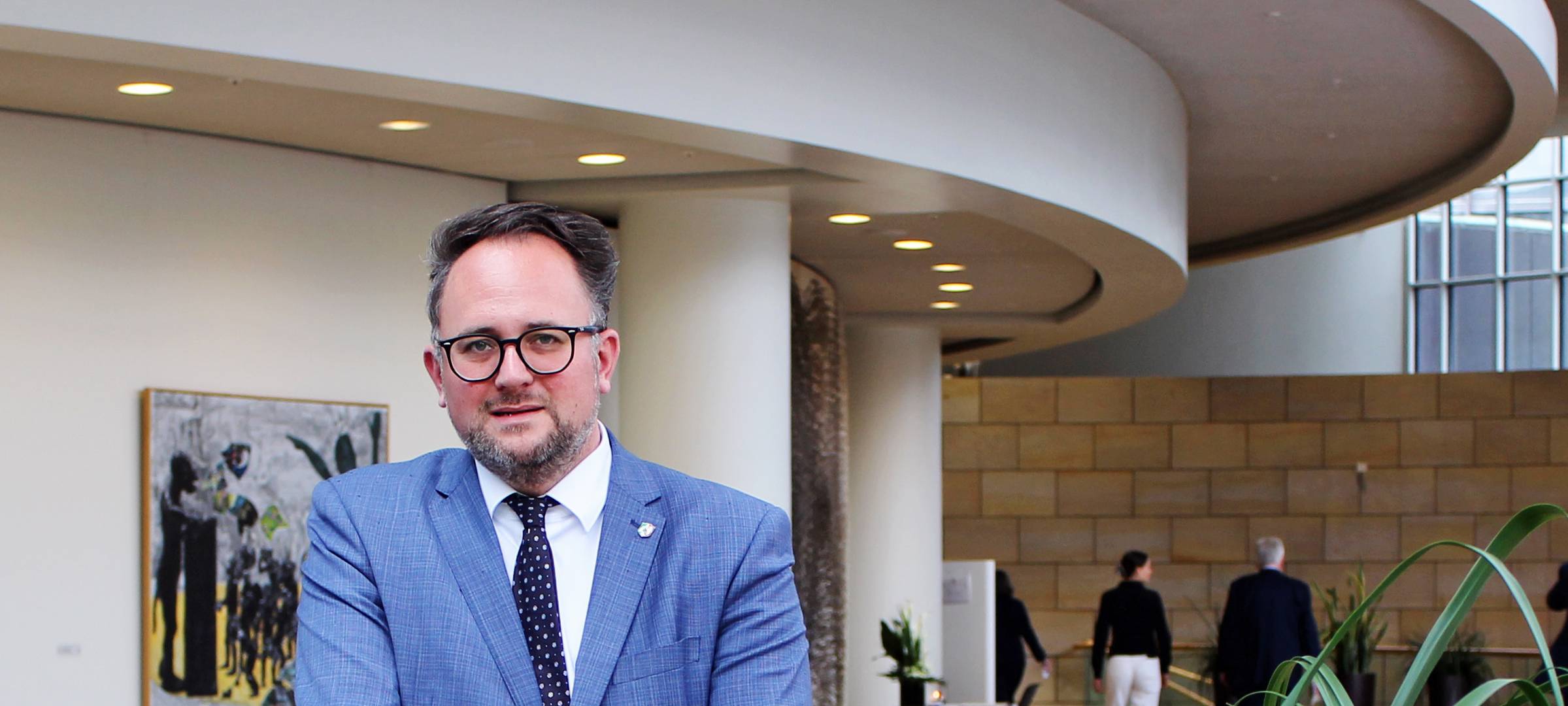 Matthias Eggers steht im mittelblauen Anzug an einem hölzernen Geländer.