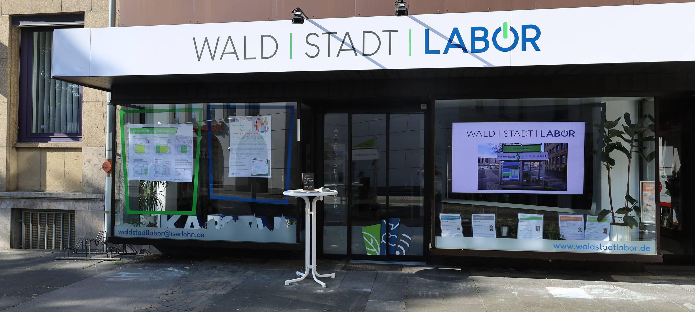 Das Bild zeigt ein kleines Ladenlokal. Auf dem Schild oben über dem Lokal steht "Waldstadtlabor".
