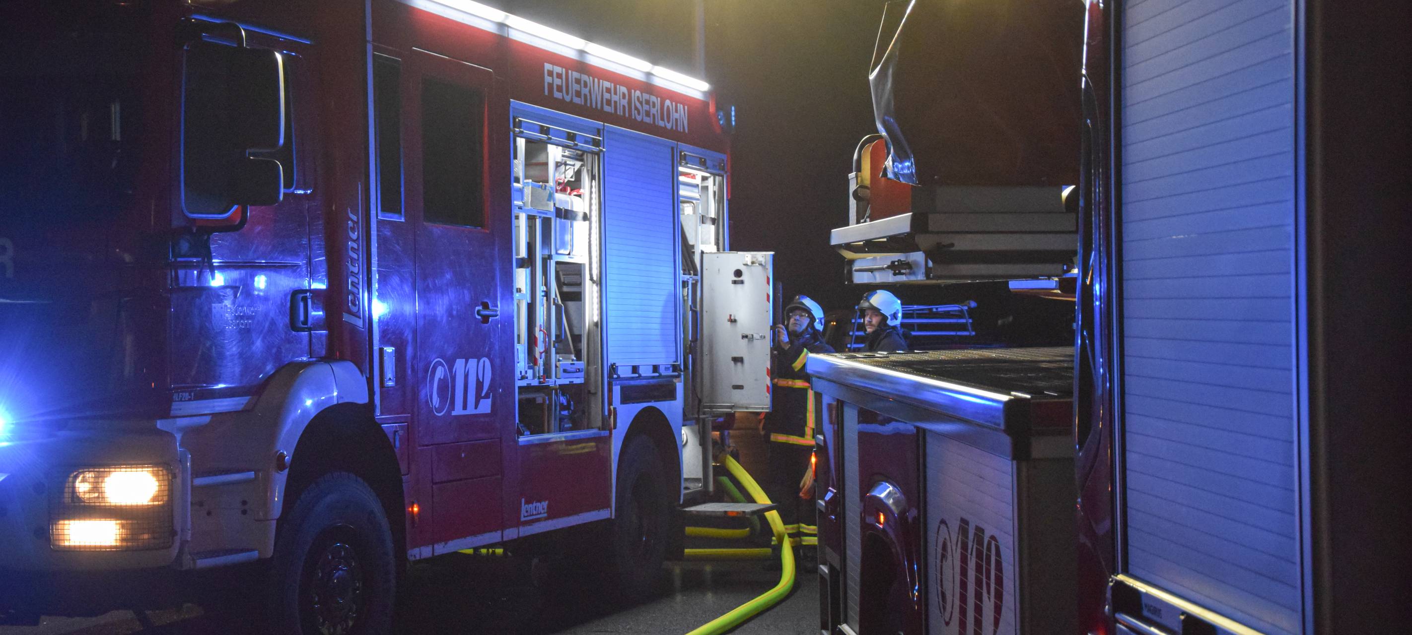 Das Bild zeigt zwei Wagen der Feuerwehr mit Blaulicht im Dunkeln.