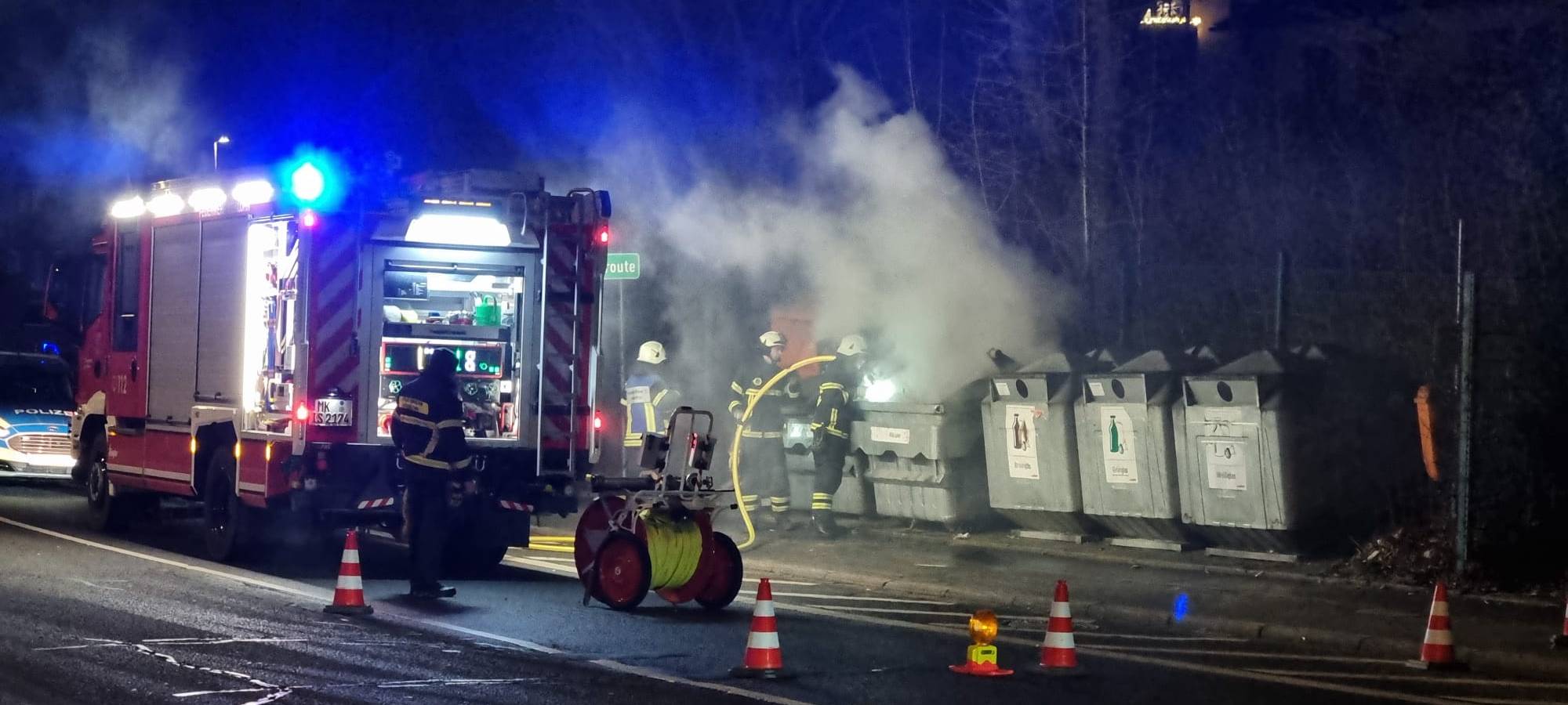 Die Feuerwehr löscht einen brennenden Altpapiercontainer.