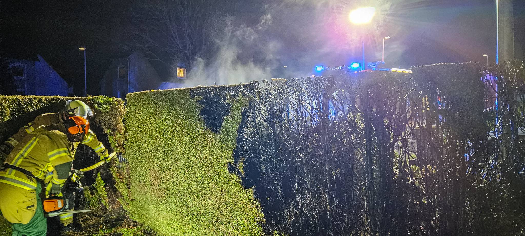 Die Feuerwehr löscht eine brennende Hecke