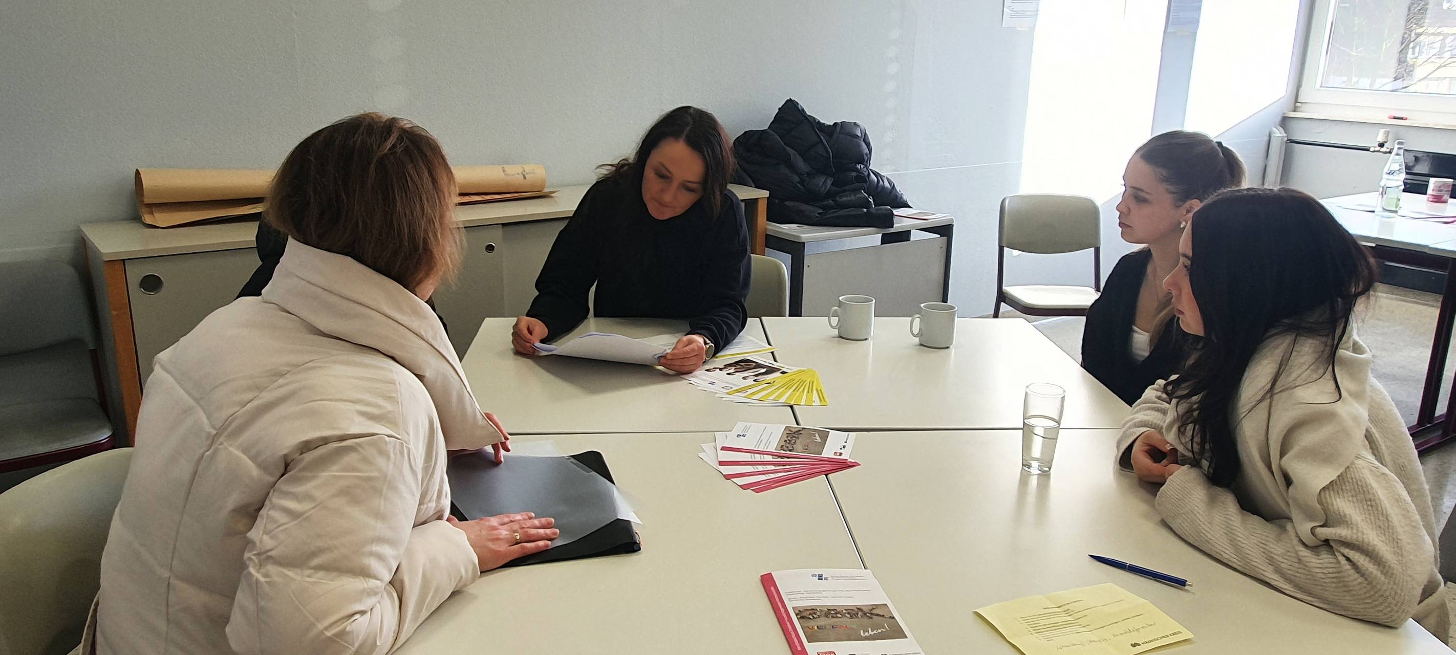 Fachlehrerin Christina Baumhoff (mitte) berät mit Unterstützung von Leonie Hammer (r) und Lara Gerlach (2.v.r.) (beide Schülerinnen der aktuellen Klasse des Beruflichen Gymnasiums Abitur in Kombination mit der Ausbildung als Erzieher(in) in der Q2) eine interessierte Mutter und ihre Tochter.