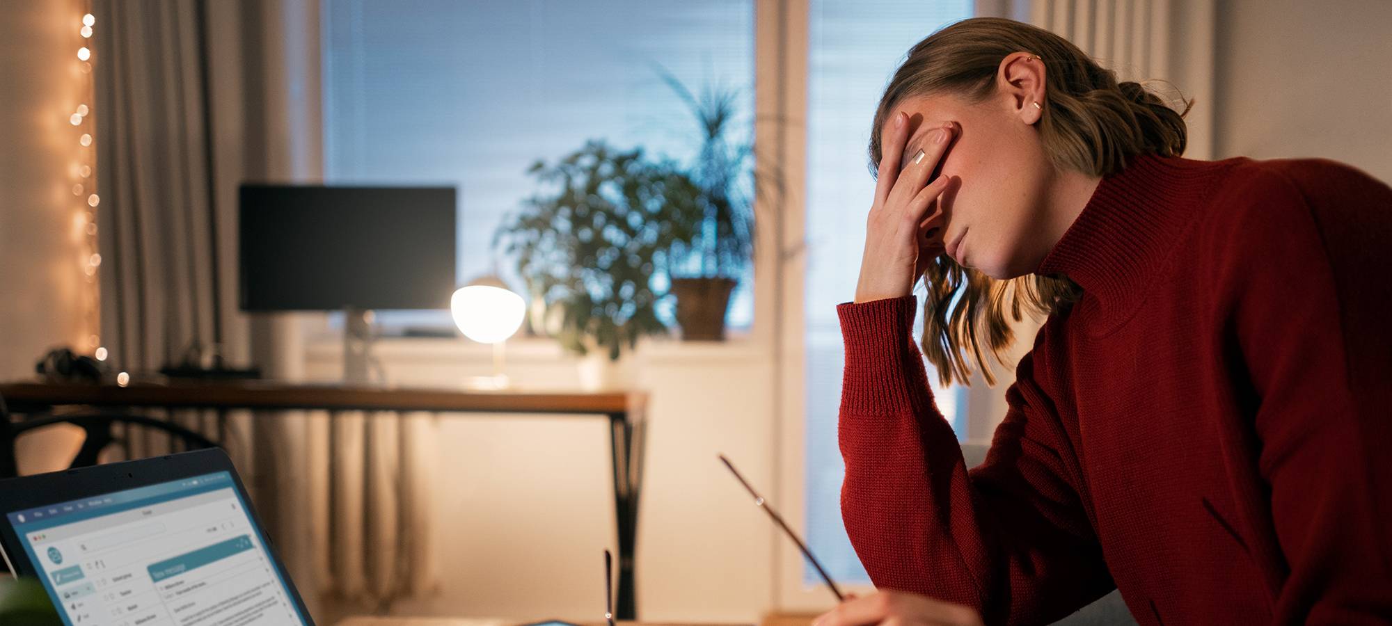 Frau sitzt spät abends am Laptop und arbeitet von zuhause
