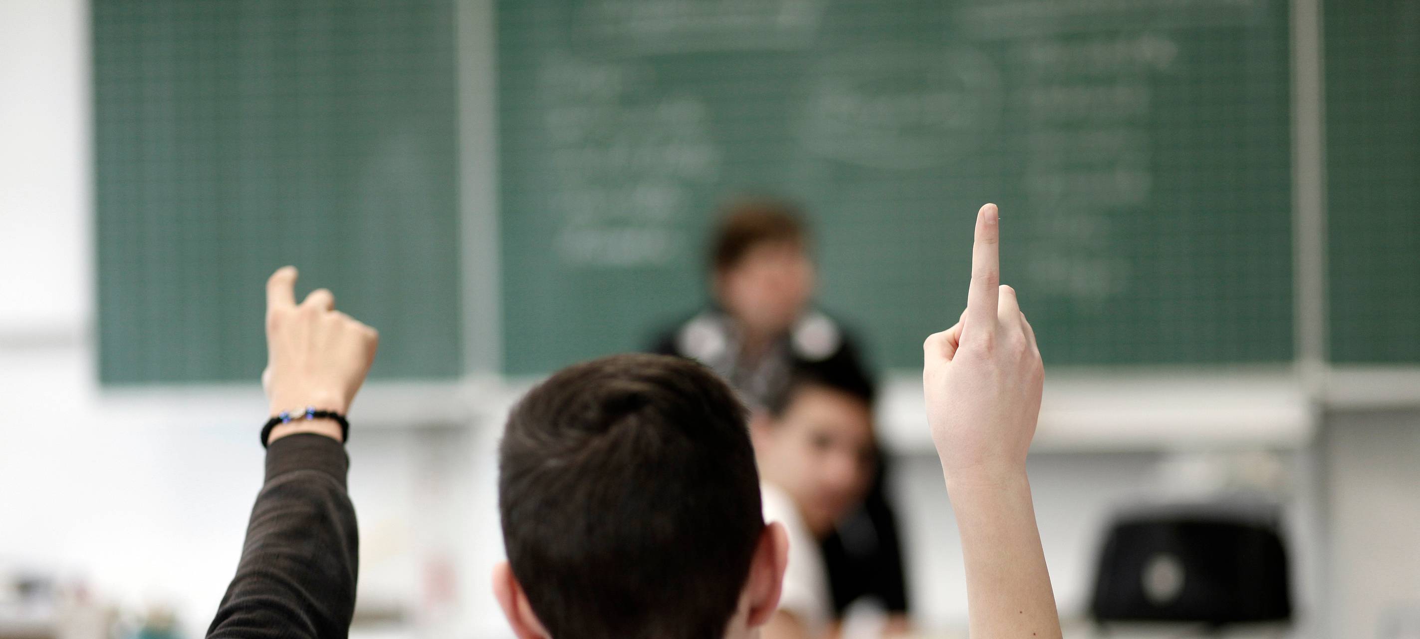 Ein Schüler hebt im Unterricht in einer Schule die Hand.