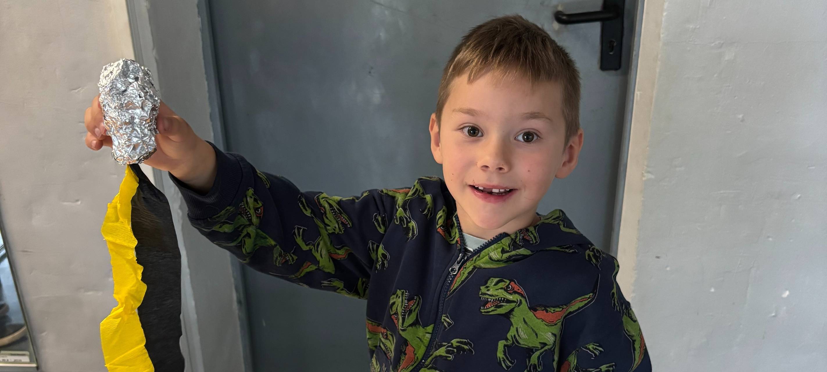 Ein Junge hält sein selbstgebasteltes Flugobjekt hoch