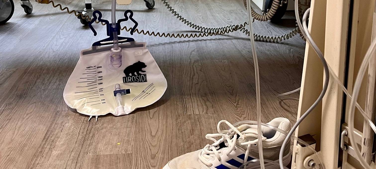 Auf dem Fußboden hat der Blasenkatheter-Beutel nix zu suchen. Infektionsgefahr!