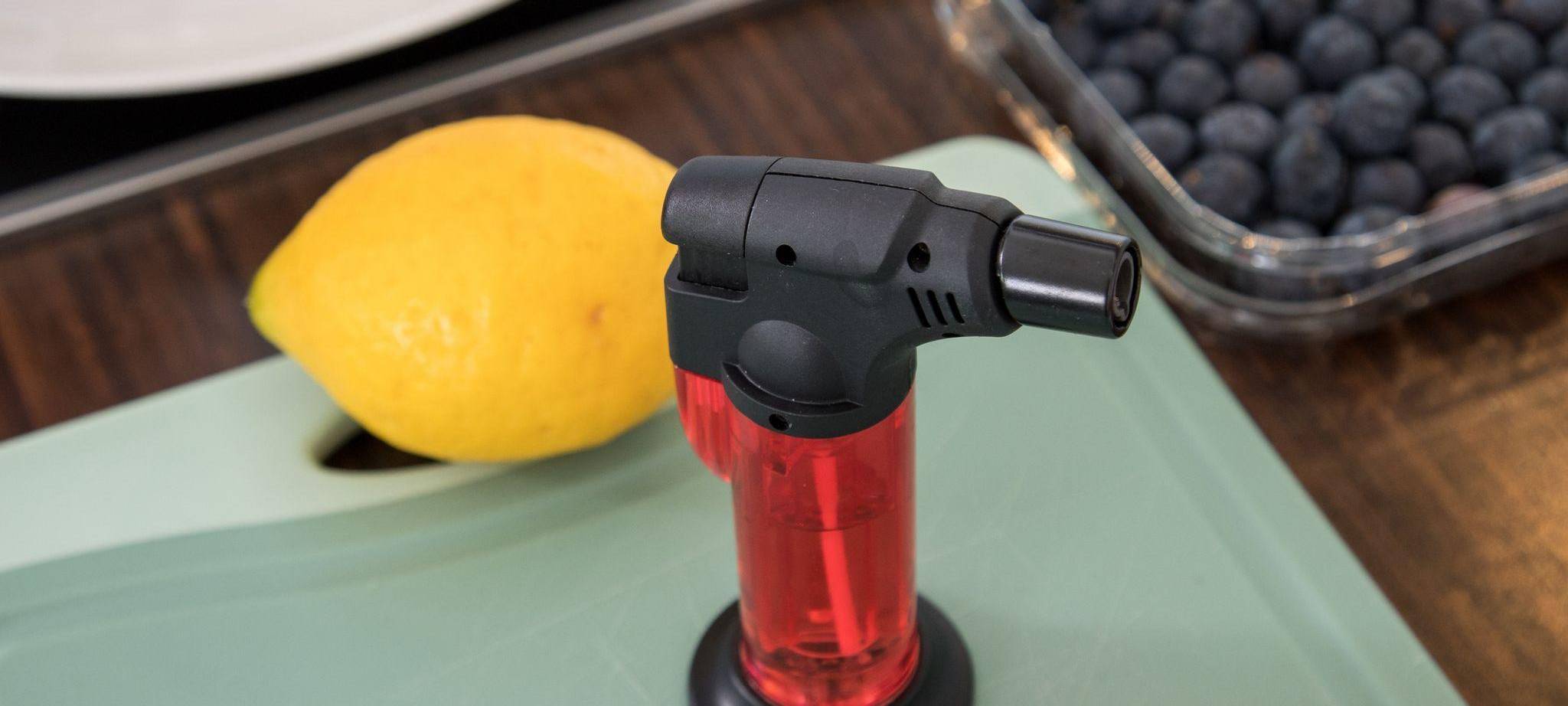 Ein Bunsenbrenner steht neben einer Zitrone und Blaubeeren