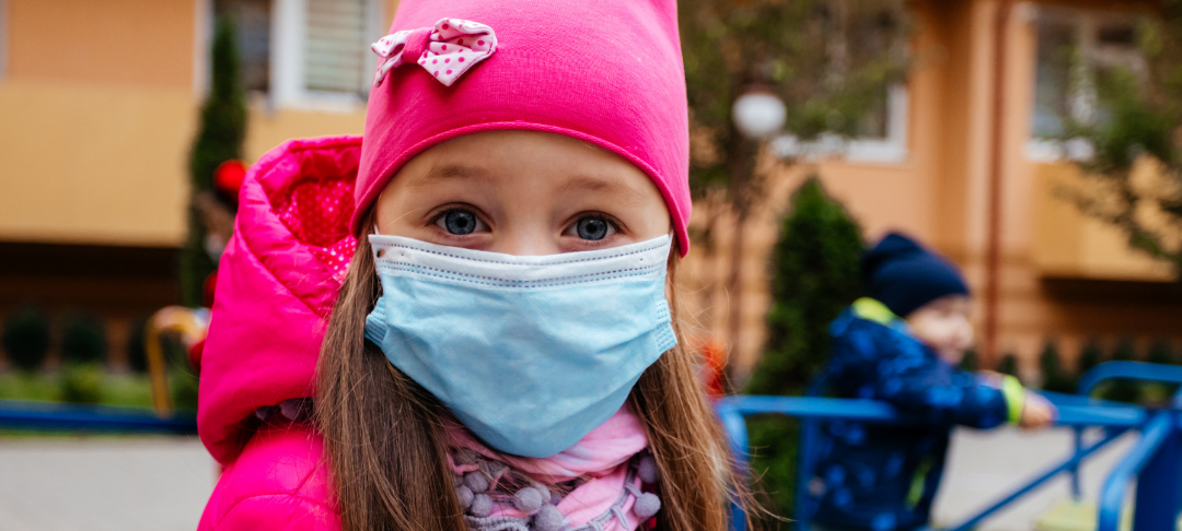 Kind mit Maske auf Spielplatz