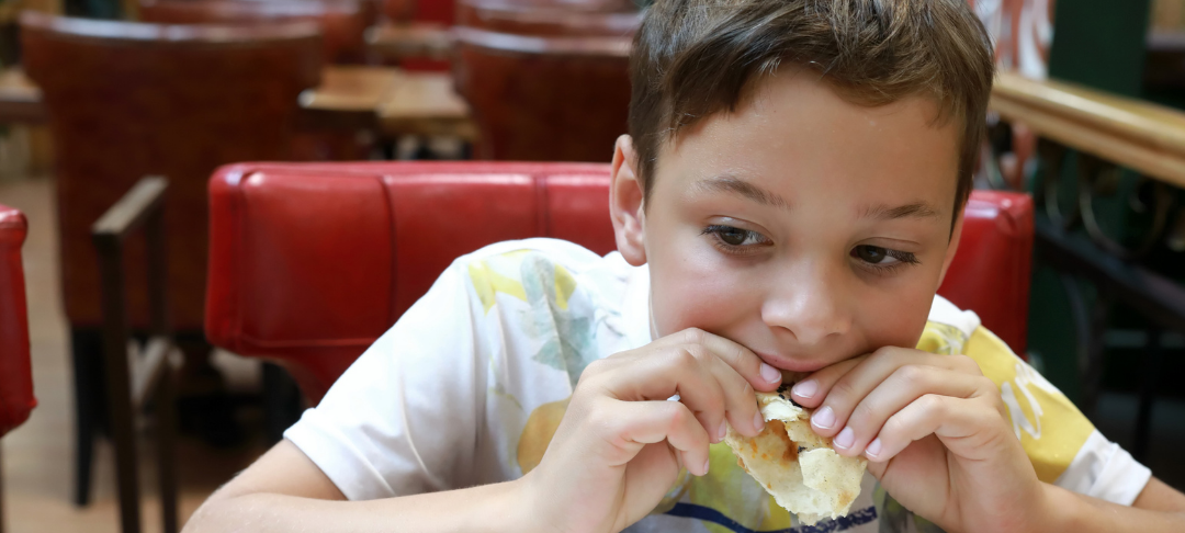 Junge sitzt im Restaurant am Tisch und isst.