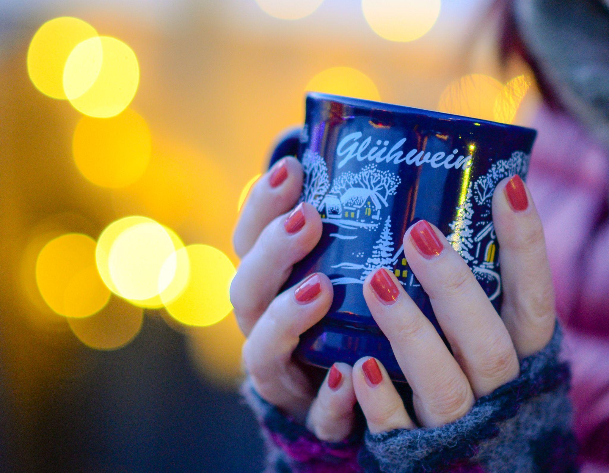 Frau hält Tasse mit Glühwein in den Händen