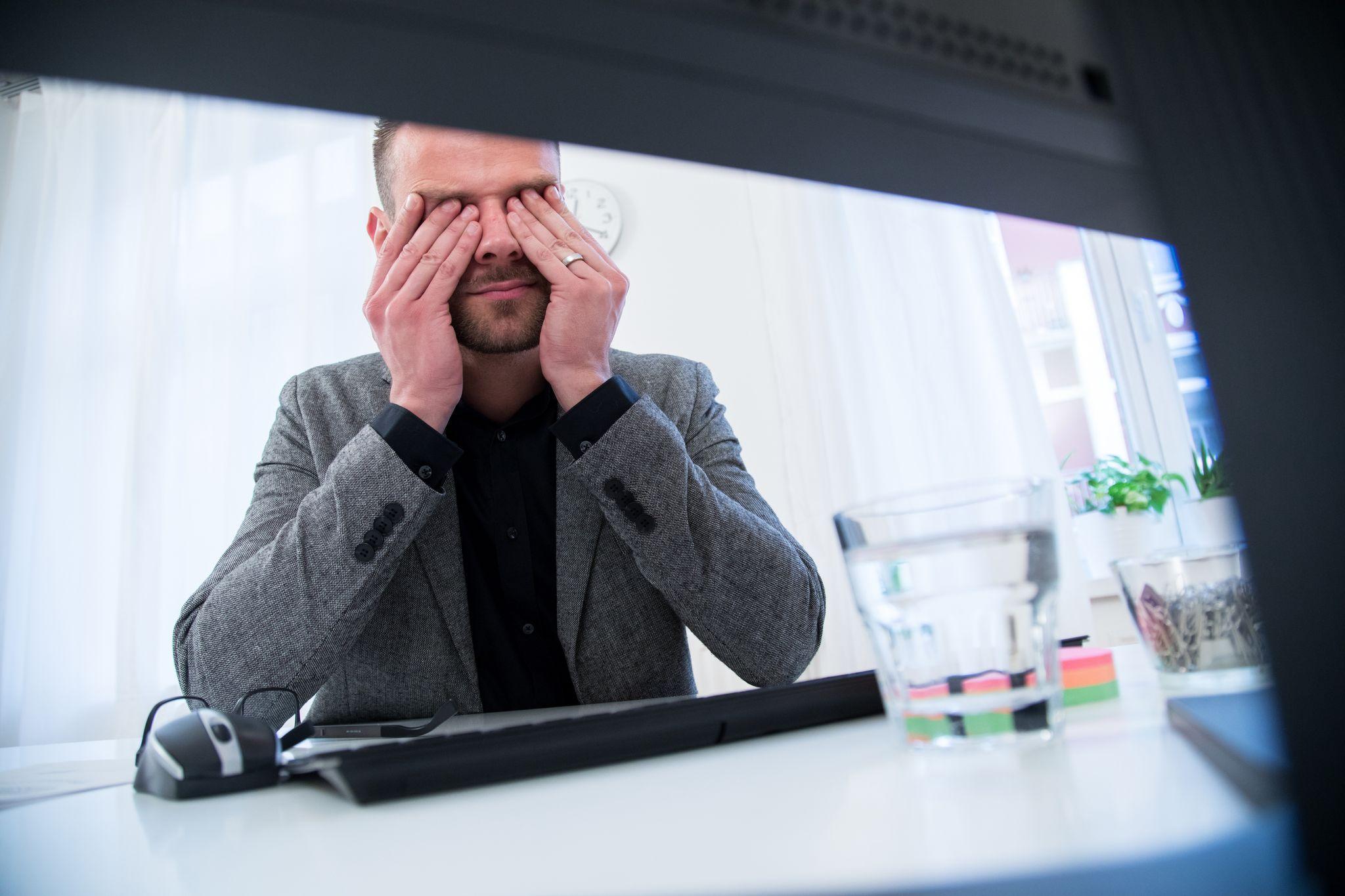 Ein Mann reibt sich die Augen am Schreibtisch